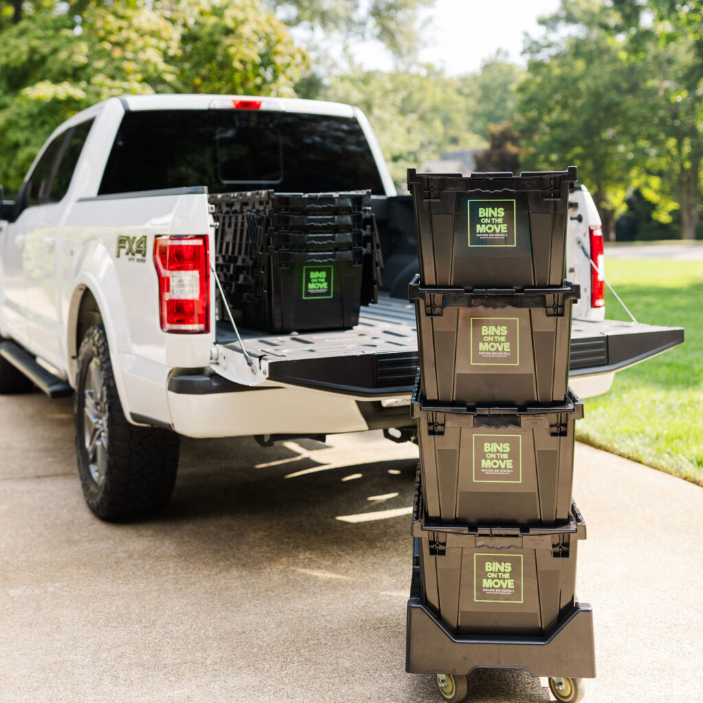 Stacked reusable moving boxes in front of truck.