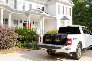 BINS ON THE MOVE reusable moving bins loaded in a pickup truck outside a home